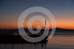 A pier at Trasimeno lake Umbria, Italy at dusk, with beautiful water reflections and warm colors