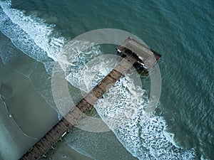 Pier at Tybee Island in Georgia surrounded by Atlantic Ocean waves as seen from drone