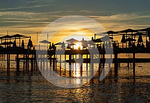 pier with umbrellas and sunbeds. silhouettes. beautiful sunset on sea.