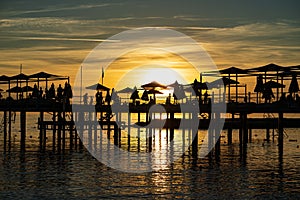 pier with umbrellas and sunbeds. silhouettes. beautiful sunset on sea.