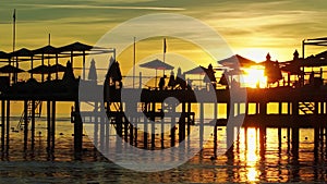 pier with umbrellas and sunbeds. silhouettes. beautiful sunset on sea.