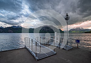 Pier in Weggis Village on Lucerne lake under dramatic clouds, Switzerland