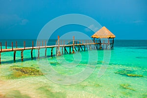 Pier and wooden gazebo by the beach. Tropical landscape with Jetty: sea, sand, rocks, waves, turquoise water. Mexico, Cancun