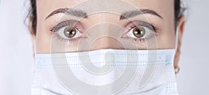 Piercing female look of brown eyes close-up. Portrait of a female doctor in a medical mask