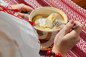 Pierogi or pyrohy, varenyky, traditional dumplings served with sour cream in bowl on wooden table.