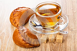 Pies with stuffing, cup of tea, spoon on saucer, sugar