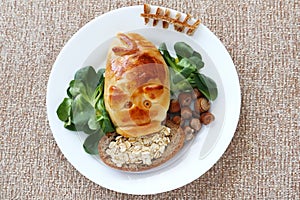 A pig baked from dough on a white plate eats grass and nuts. The concept is a fun food for kids.