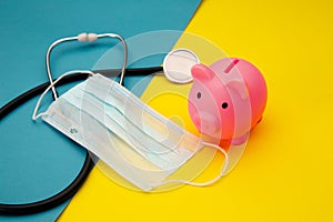 Pig moneybox, face mask and stethoscope on colorful background. Spending money on pills and expensiveness of medicine