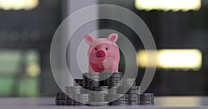 Pig piggy bank balancing on a stack of silver coins