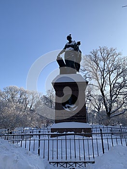 a pigeon perched on the head of the Cleo monument in winter