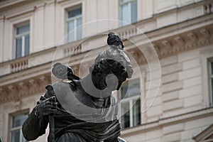 Pigeons sit on the head of an ancient marble sculpture of an ancient hero