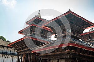 Pigeons sitting on the brown tiled roof of an ancient Hindu temple. Shikhara peak of the temple against the blue sky