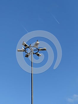 Pigeons on the street lamp with two airplanes with vapour trails on the sky in background