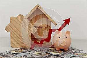 Piggy bank with arrow up and wooden house models on dollar banknotes, Saving or loan for buy house or real estate owner