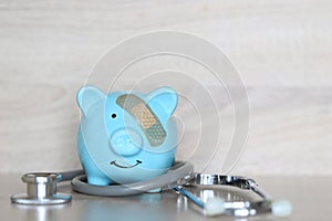 Piggy bank attached to the plaster on the head and stethoscope on wooden background, Save money for Medical insurance and Health