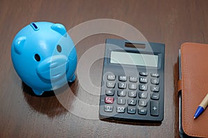Piggy bank calculator with deposit put account on wood table.
