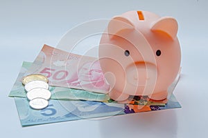 A Piggy bank with Canadian currency on a white table. Concept: Canadian economy. Canadians saving money.