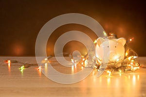 Piggy bank with Christmas string lights on happy December festival, Enjoy savings for spending money on the holiday`s concept