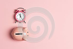 Piggy bank and classic alarm clock on pink background. Time to saving, money, banking concept