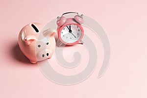 Piggy bank and classic alarm clock on pink background. Time to saving, money, banking concept