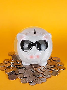 Piggy bank with coin pile on yellow background, space for text. Finance, saving money. Business to success and saving for