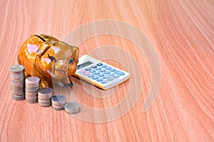Piggy bank, coins and calculator out on wood table