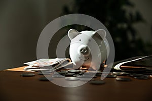 Piggy bank with coins and money banknotes on table