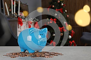 Piggy bank with coins on table in living room decorated for Christmas.