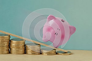 Piggy bank on decreasing piles of coins - Concept of finance and losing money