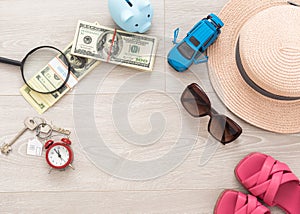 A piggy bank with dollar bills in a travel setting. In the composition of the image: Sun Hat, Alarm Clock. Concept of