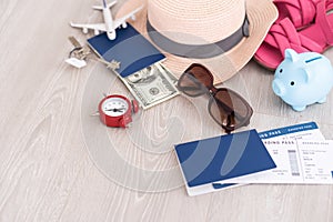 A piggy bank with dollar bills in a travel setting. In the composition of the image: Sun Hat, Alarm Clock. Concept of