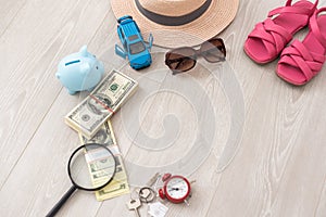 A piggy bank with dollar bills in a travel setting. In the composition of the image: Sun Hat, Alarm Clock. Concept of