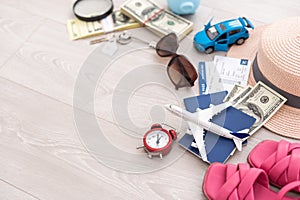 A piggy bank with dollar bills in a travel setting. In the composition of the image: Sun Hat, Alarm Clock. Concept of