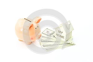 Piggy bank, dollars banknotes and home model on white background