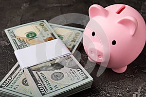 Piggy bank with dollars on a black texture background.Money saving concept.