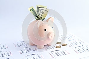Piggy bank with dollars and coins on calendar, deposit or savings money concept