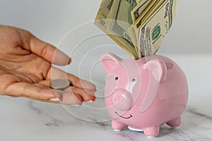 a piggy bank with dollars and a woman's hand holding out euro coins on the office table. economy, crisis and inflation. Cost