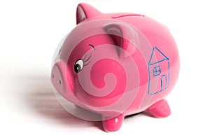 Piggy bank with drawn house. Save up for a house concept. Closedup, white background, side view