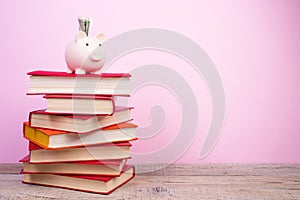 Piggy bank in glasses and books on pink background. open book. Tuition payment. Brainwork. Back to School