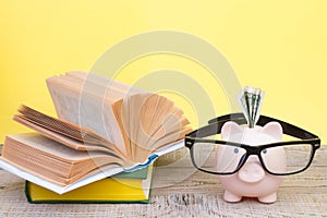 Piggy bank in glasses and books on yellow background. open book. Tuition payment. Brainwork. Back to School