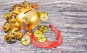 Piggy bank with golden coins and chinese ornament on the wooden table