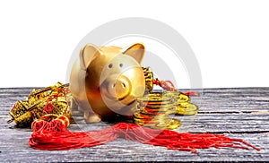 Piggy bank with golden coins and chinese ornament on the wooden table