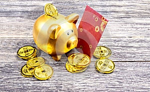 Piggy bank with golden coins and red envelopes on the wooden table