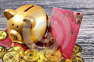 Piggy bank with golden coins and red envelopes on the wooden table
