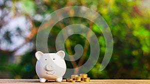 Piggy bank and a golden coins stack on old wooden table.