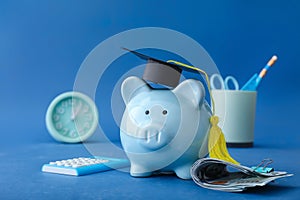 Piggy bank with graduation hat and money on color background. Tuition fees concept