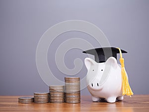 Piggy bank with graduation hat and stack of coins. The concept of saving money for education, student loan, scholarship, tuition