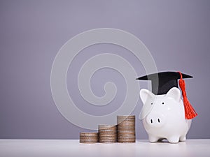 Piggy bank with graduation hat and stack of coins. The concept of saving money for education, student loan, scholarship, tuition