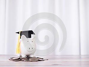 Piggy bank with graduation hat on stack of coins. The concept of saving money for education, student loan, scholarship, tuition