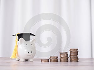 Piggy bank with graduation hat and stack of coins. The concept of saving money for education, student loan, scholarship, tuition